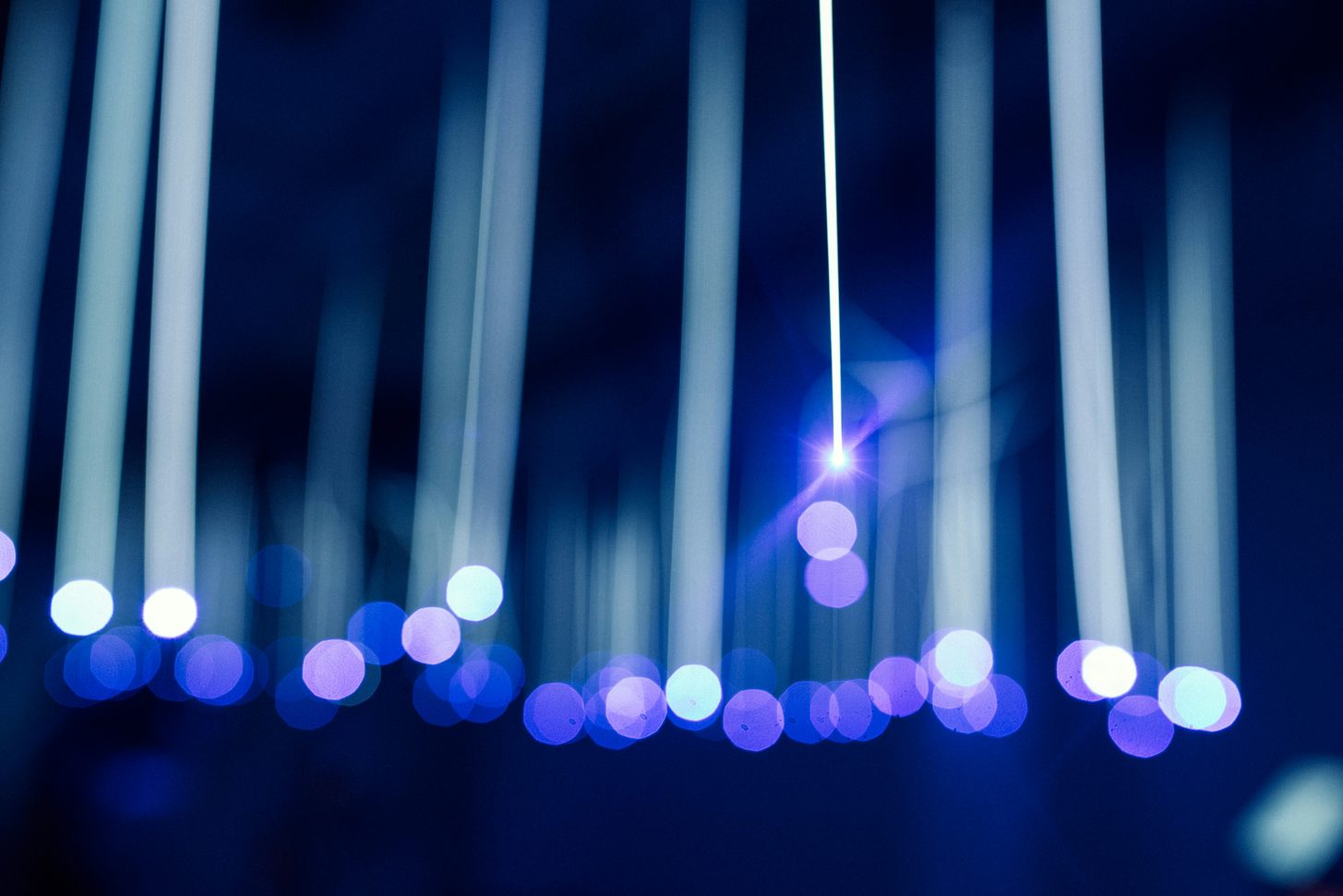 Abstract long-exposure photograph of vertical white and blue light streaks against darkness